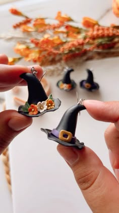 two small witches hats are being held by someone's hands with tiny flowers in the background