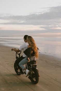 a man riding on the back of a motorcycle down a beach next to the ocean