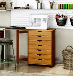 a sewing machine sitting on top of a wooden table next to a shelf filled with craft supplies