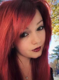 a woman with red hair and piercings on her nose is posing for the camera