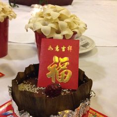 there is a cake on the table with chinese writing and flowers in pots next to it