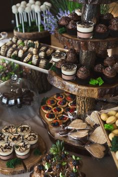 an assortment of desserts and pastries displayed on wooden trays at a buffet table