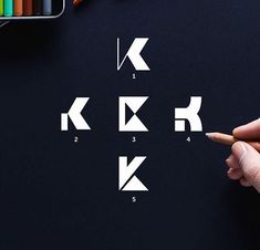 a person's hand is pointing to the letters k and k on a black surface