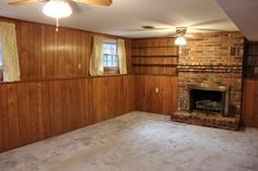 an empty living room with wood paneling and a fireplace