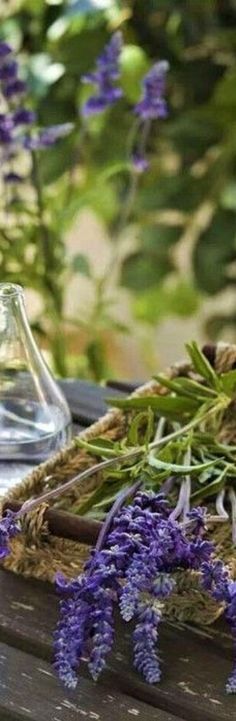 some lavender flowers are sitting on a table next to a glass vase with water in it