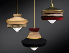 three hanging lights in different colors and shapes on a black background, one is red, the other is gold