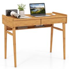 a laptop computer sitting on top of a wooden desk next to a potted plant