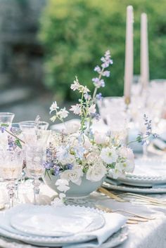 the table is set with plates, silverware and flowers in vases on it