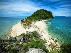 people standing on the edge of a cliff overlooking an island