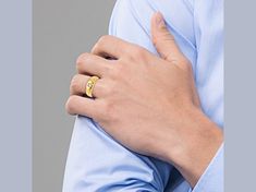 a man wearing a gold wedding band with his hand on his chest