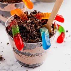 two cups filled with dirt, gummy bears and toothbrushes on top of each other