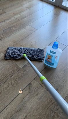 a mop laying on the floor next to a bottle of cleaner