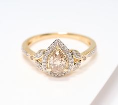 a yellow gold ring with a pear shaped diamond surrounded by small white and brown diamonds