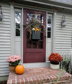 the front door is decorated with flowers and pumpkins