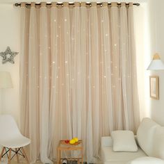 a living room filled with furniture and a window covered in sheer curtaining next to a white chair