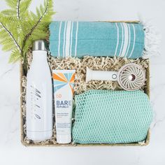 an assortment of personal care items displayed in a basket on a marble countertop with fern