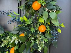 an orange wreath hanging on the front door with blue berries and greenery around it