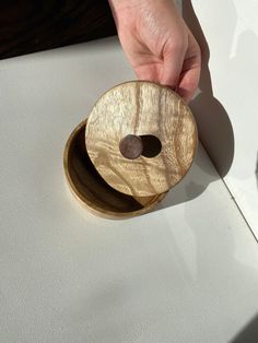 a person holding a wooden object in their hand on a white surface with sunlight coming through the window