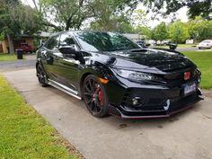 a black car parked on the side of a road next to a tree and grass