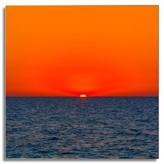 the sun is setting over the ocean on an orange and blue sky day or night