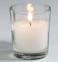 a lit candle sitting in a glass filled with water