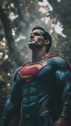 a man dressed as superman standing in the woods with his head turned to look up