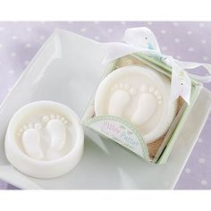 two baby footprints are on a plate next to a soap dish with the lid open