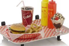 a tray that has some food on it with drinks and ice cream in the background