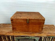 an old wooden box sitting on top of a book shelf in front of a white wall