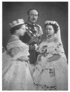 an old black and white photo of two women in wedding dresses with a man standing next to them