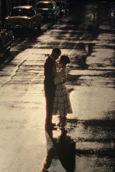 a man and woman are standing in the rain holding an umbrella while they look at each other