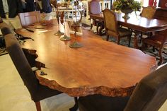 a large wooden table surrounded by chairs in a room with other people looking at it