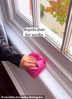 a person wiping the windowsill with a cloth