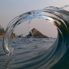 an ocean wave with some rocks in the background