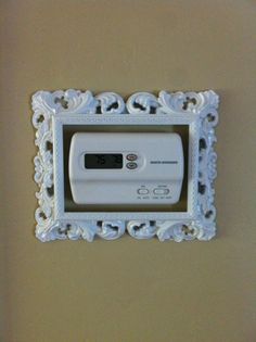 an electronic device mounted to the side of a wall in a white frame with ornate designs