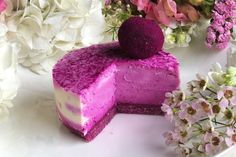 a purple cake sitting on top of a white plate next to pink and white flowers