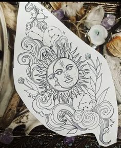 an image of a sun and moon tattoo design on paper with candles in the background