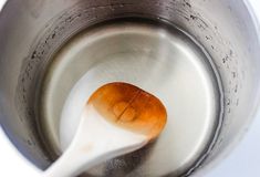 a wooden spoon in a metal cup filled with water