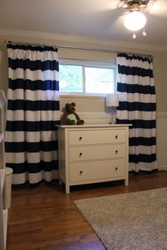 a white dresser sitting in front of a window next to a rug on top of a hard wood floor