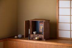 a small wooden cabinet sitting on top of a table next to a vase and candle