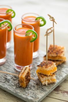 small sandwiches with toothpicks are on a slate board and garnished with limes