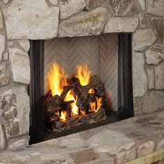 a fire burning in a fireplace next to a stone wall