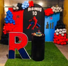 a birthday party with balloons and decorations on the grass, including a spiderman cake