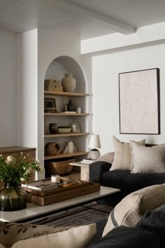 a living room filled with furniture and a painting on the wall above it's bookshelf