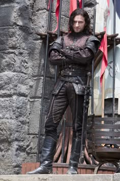 a man dressed in armor standing next to a gate