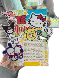 someone holding up a hello kitty book with many different stickers on it's cover