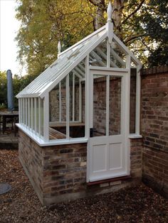 a small white building with a brick wall and glass doors on the side of it