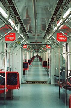 an empty train car with red seats and signs