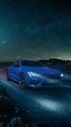 a blue sports car driving on a road at night with stars in the sky above