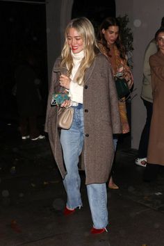 a woman in jeans and heels is walking down the street